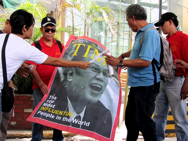Union leaders bring in front of labor department a spoof of Time magazine cover citing Pres. Aquino as one of 100 'most influential persons.'
