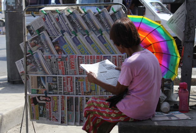  A vendor whiles away a slow selling day by reading her own merchandise. (Photo by POM CAHILOG-VILLANUEVA/ Bulatlat.com)