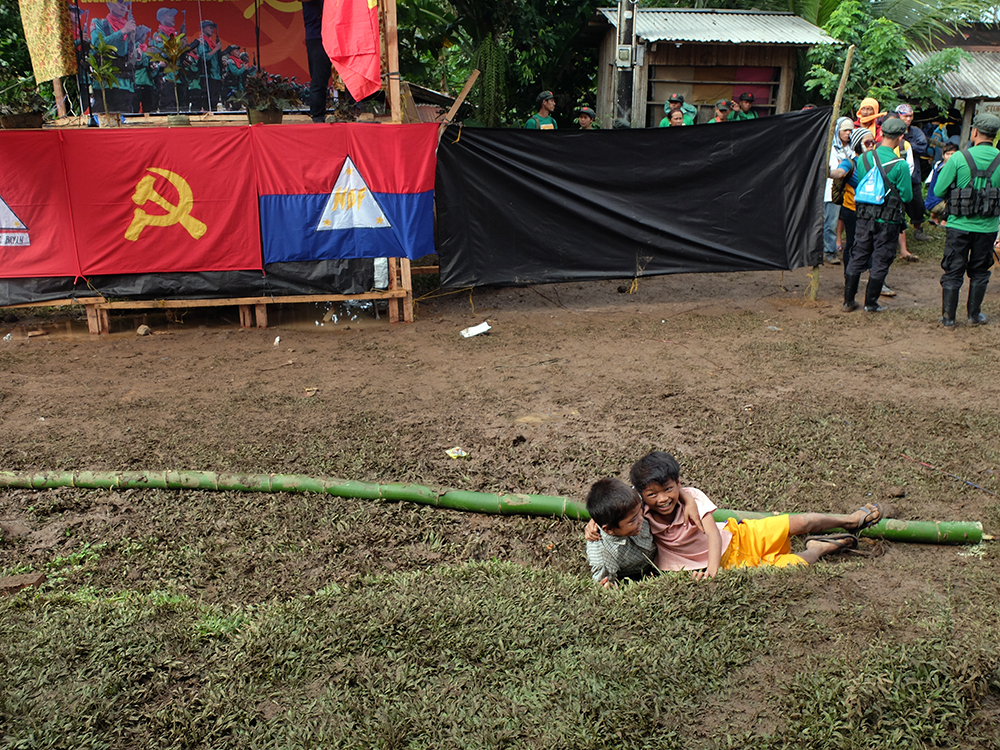 Two young boys slip on the muddy ground and laugh their heads off, obviously having fun and wanting the program to start already.  (Kitcharao, Agusan del Norte)