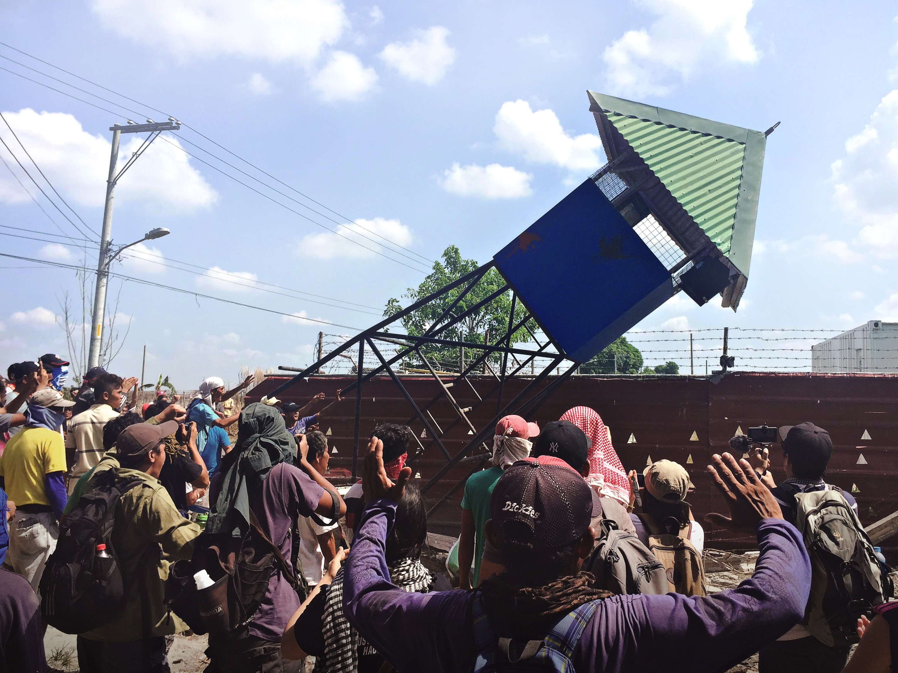 The watch tower inside the RCBC compound topples down amid cheering farm workers inside Hacienda Luisita on April 24, 2017 (Photo by Amihan Mabalay/Bulatlat)